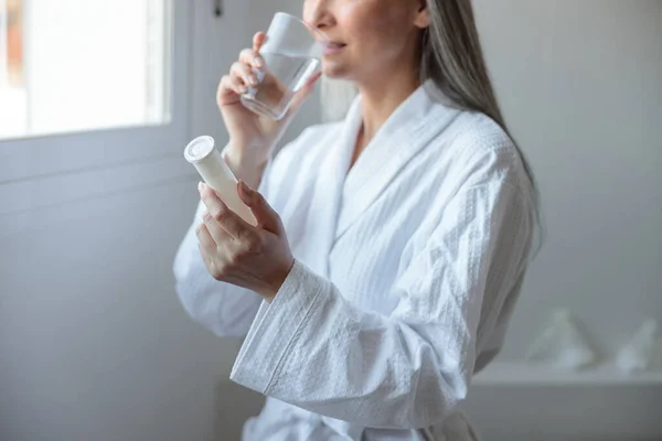 Mulher bonita em roupão branco tomando vitaminas — Fotografia de Stock