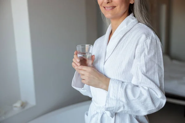 Close-up de senhora em roupão de banho com copo de água — Fotografia de Stock