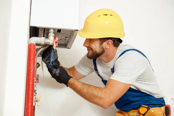 Tampilan samping tukang, teknisi menggunakan obeng saat memperbaiki ketel uap atau pemanas air, bekerja pada sistem pemanas di apartemen — Stok Foto