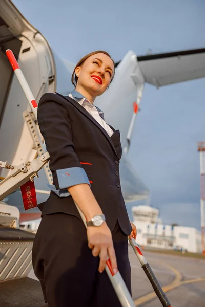 Veselá žena letuška stojící na schodech letadla — Stock fotografie