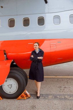 Havaalanında özel uçağın yanında duran neşeli kadın.