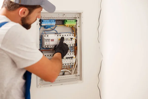 Teknisi listrik dalam seragam terlihat fokus saat bekerja dalam sebuah switchboard dengan sekering — Stok Foto