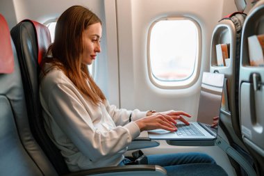 Yolcu uçağında dizüstü bilgisayar kullanan genç bir kadın