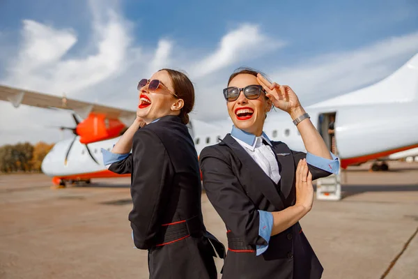 Dua pramugari wanita ceria berdiri di luar bandara — Stok Foto