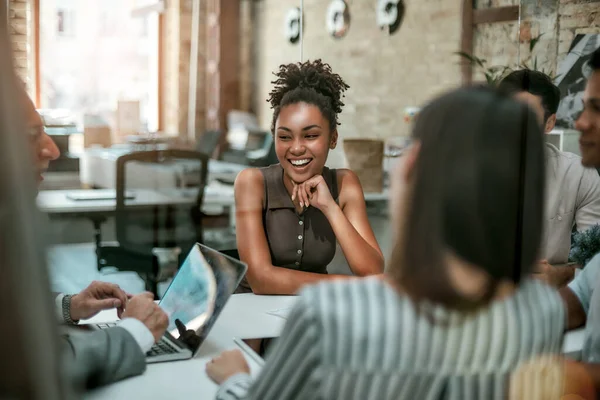 Siamo una squadra sola. Giovane e allegra donna afro americana sorridente mentre ha un incontro con i colleghi nell'ufficio moderno — Foto Stock