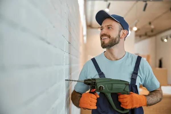 Cheerful male worker drilling wall with hammer drill — Stock Photo, Image