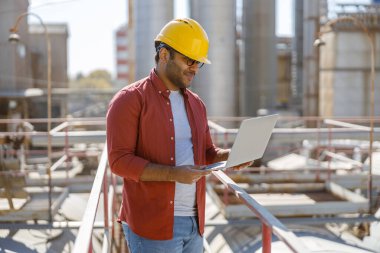 Fabrikada dizüstü bilgisayar kullanan genç sanayi mühendisi