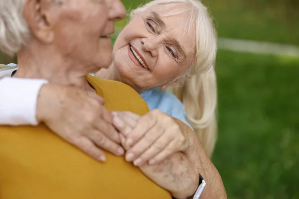 Зрелая женщина обнимает партнера, тренирующегося вместе в зеленом парке — стоковое фото