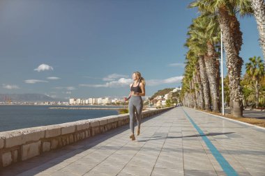 Genç atletik kadın deniz kenarında egzersiz yapıyor.