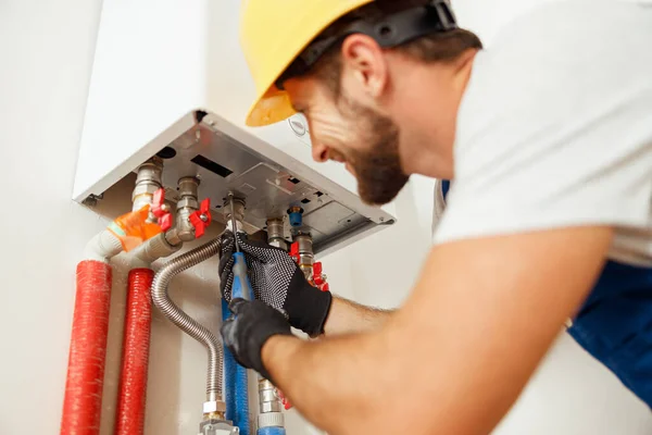 Fecho do encanador usando chave de fenda durante a fixação de caldeira ou aquecedor de água, trabalhando no sistema de aquecimento no apartamento — Fotografia de Stock