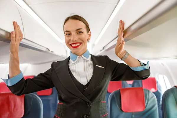 Χαρούμενη γυναίκα αεροσυνοδός στέκεται στο σαλόνι επιβατών αεροσκαφών — Φωτογραφία Αρχείου