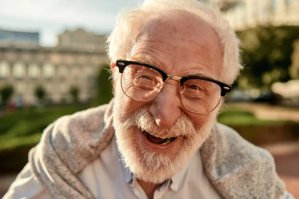 Potret pria janggut tampan berkacamata menatap kamera dan tersenyum sambil berdiri di luar ruangan pada hari yang cerah — Stok Foto