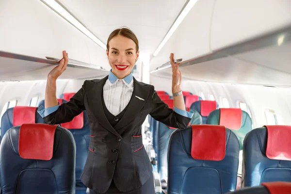 Veselá letuška stojící v salónu pro cestující — Stock fotografie