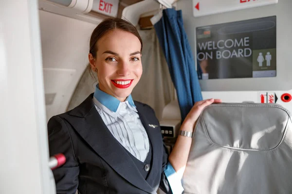 Allegro assistente di volo donna in piedi in cabina d'aereo — Foto Stock
