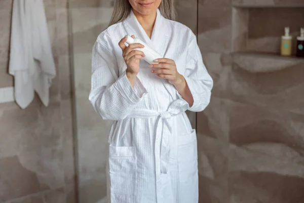 Lächelnde Frau hält Kosmetikfläschchen in der Dusche — Stockfoto
