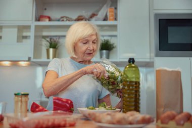 Evde salata yapan yaşlı bir kadın.