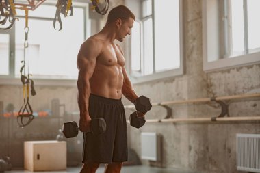 Vücut geliştirme merkezinde kol egzersizi yapan yakışıklı adam.