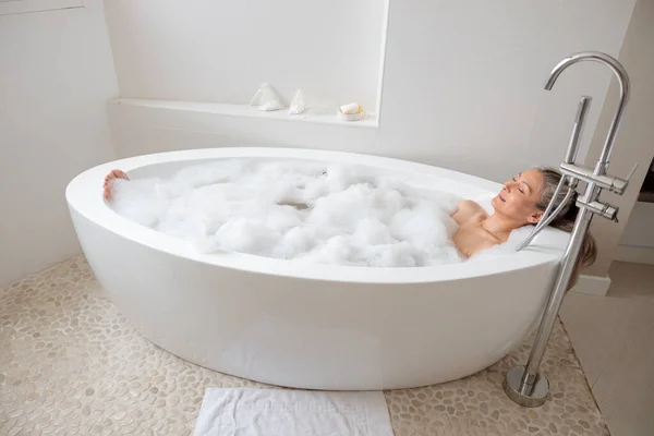 Dame liggend in de badbuis in de badkamer — Stockfoto
