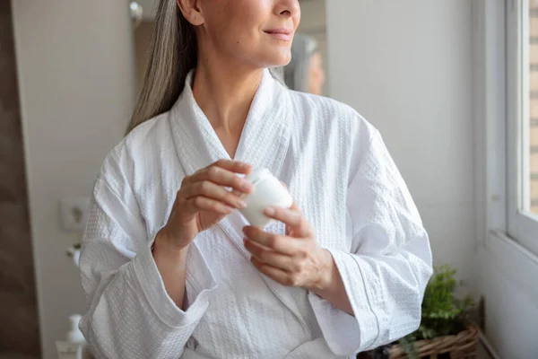 Foto de cerca de manos de mujer suave sosteniendo frasco cosmético —  Fotos de Stock