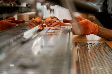 Erkek eller tornavidayla kahve makinesini tamir ediyor.