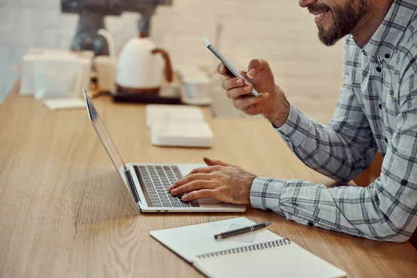 Pria ceria menggunakan ponsel dan laptop di kafe — Stok Foto