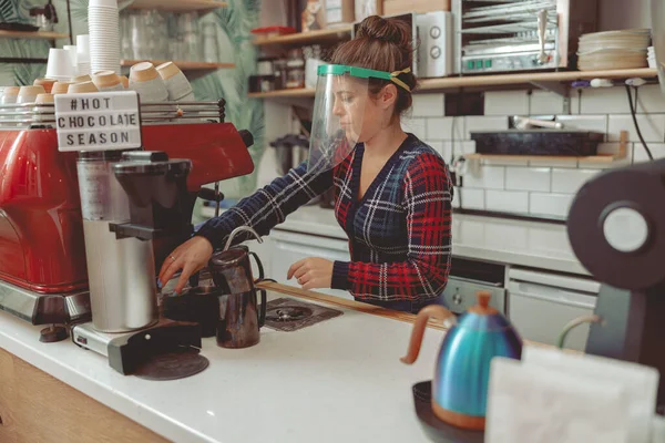 Senhora atraente em viseira protetora trabalhando no café durante a pandemia — Fotografia de Stock