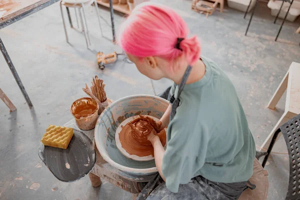 Jonge vrouw werkt op aardewerk wiel in keramiek workshop — Stockfoto