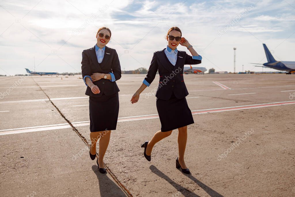 Cheerful women flight attendants walking down airport