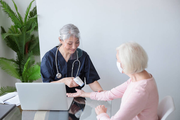 Doctor in protective visor examining patient at home