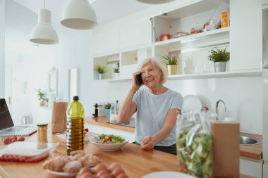 Mutlu, yaşlı bir kadın cep telefonuyla konuşuyor.