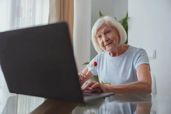 Портрет радісної старшої жінки з ноутбуком в приміщенні — стокове фото