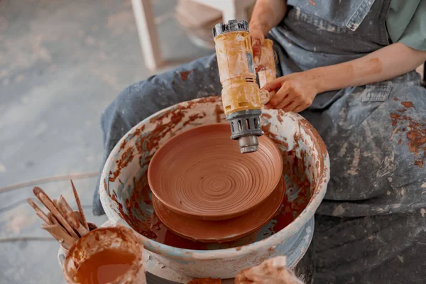 Jonge pottenbakker maakt keramische schotel in kunststudio — Stockfoto