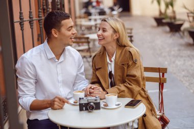 Bir çift randevu sırasında kafe masasında otururken gülüyor.