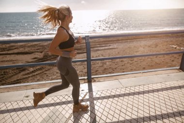 Sportif genç dişi güzel sahil boyunca koşmaktan zevk alıyor.