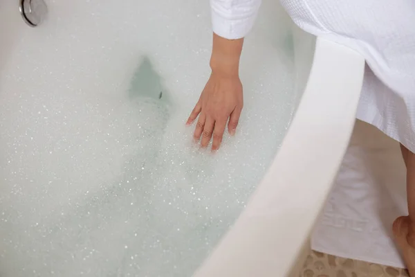 La signora sta testando la temperatura dell'acqua in bagno — Foto Stock