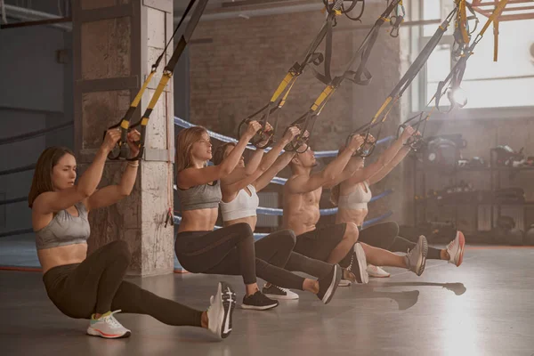 Group of young fitness people using fitness straps in sports club — Stock Photo, Image
