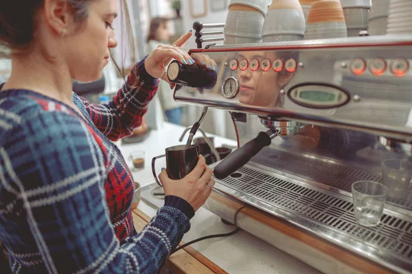 Jovem mulher espuma de leite para latte na máquina de café — Fotografia de Stock