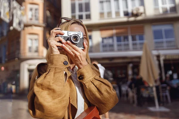 Retrato de mujer sonriente sosteniendo la cámara retro mirando a la ranura de visualización — Foto de Stock