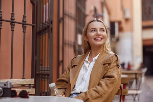 Potret wanita tersenyum duduk di meja kafe jalanan — Stok Foto