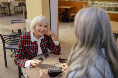 Kadın arkadaşlar sokak kafesinde sohbet ediyorlar.