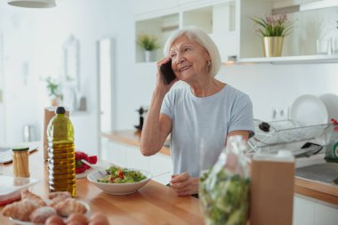 Emekli kadın ev mutfağında iletişim kuruyor.
