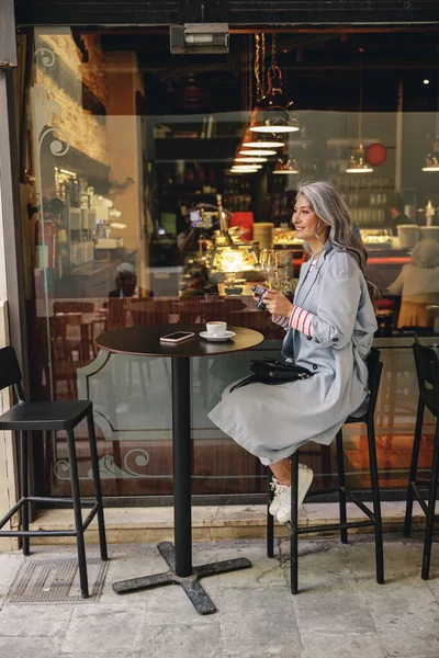 Kentli kafede oturan kendinden emin olgun bir kadın. — Stok fotoğraf