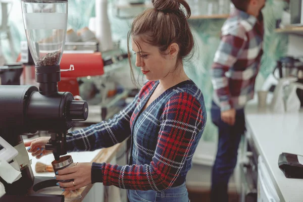 Mulher barista trabalhando em café perto moedor de café — Fotografia de Stock