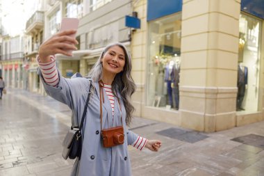 Kadın fotoğrafçı şehir merkezinde fotoğraf çekiyor.
