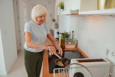 Yaşlı kadın mutfakta yemek hazırlıyor.