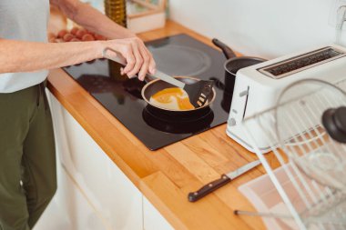Evde mutfakta yemek pişiren yaşlı bir kadın resmi