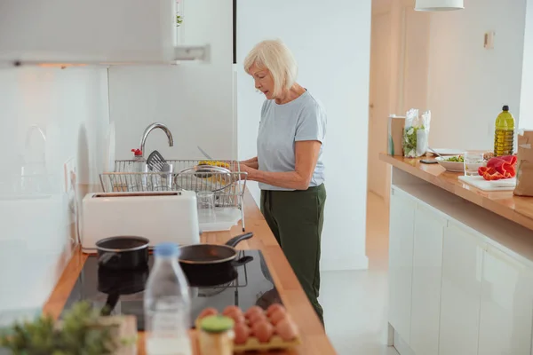 Emeklilik çağındaki kadın evde mutfak temizliği yapıyor. — Stok fotoğraf