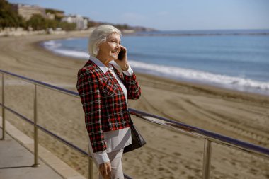 Şehir yaşlısı kadın deniz kenarında dinleniyor.
