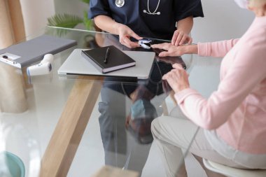 Kadın pediatrist evde yaşlı kadını muayene ediyor.