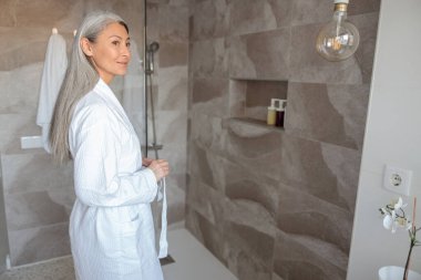 Bornozlu çekici kadın duş almaya hazırlanıyor.